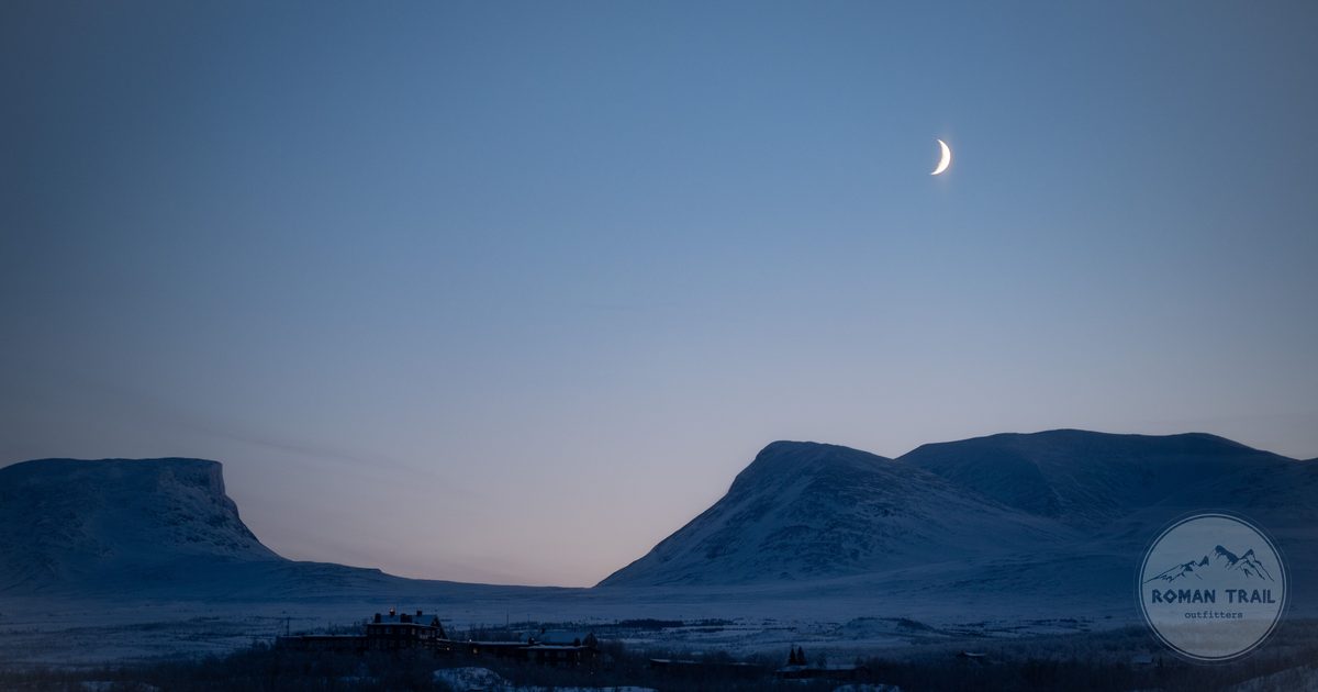 Winter twilight and a crescent moon over the snowy peaks at Abisko, Sweden