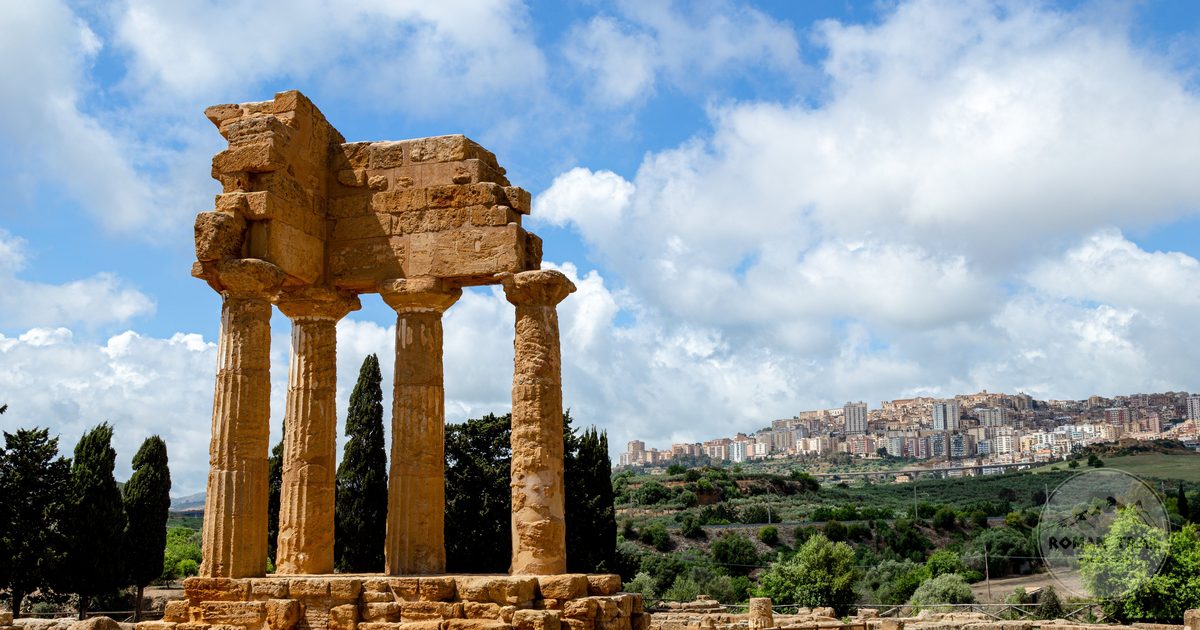 Greek temple ruins with the city of Agrigento on the ridge behind, Agrigento packing list for women by Roman Trail Outfitters