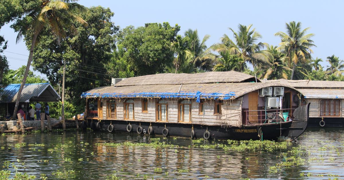 A houseboat passing dense palms on a Kerala backwater channel, Alleppey packing list for women by Roman Trail Outfitters