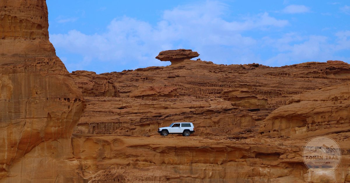 A vehicle below sandstone cliffs at Al-Ula, Saudi Arabia