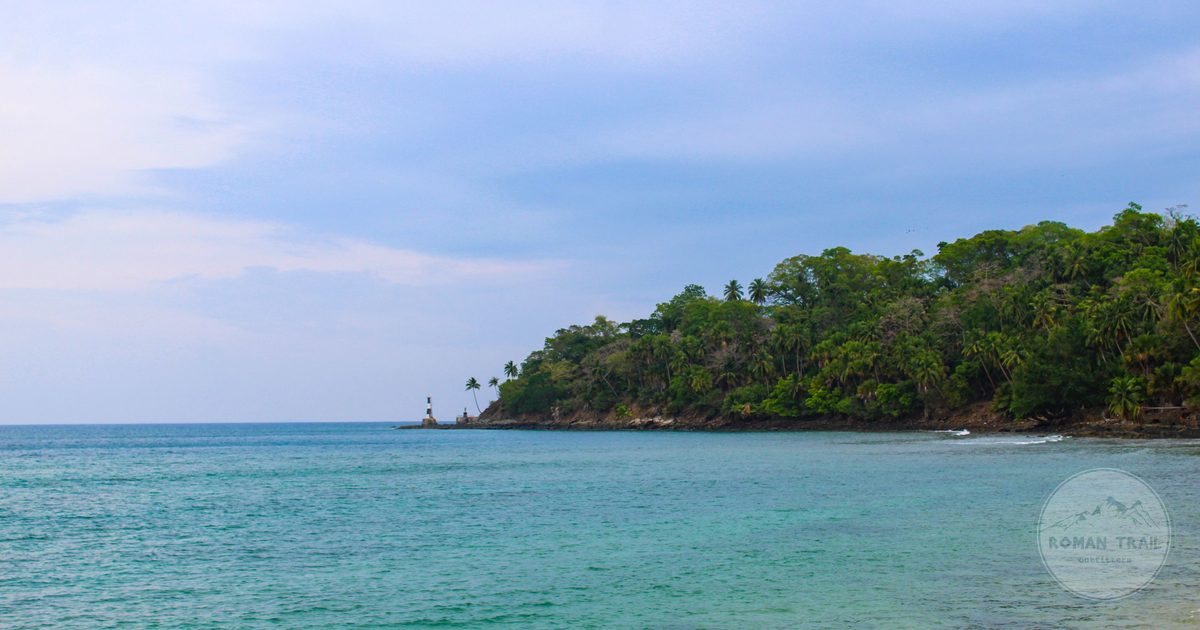 A lighthouse and forested coastline in the Andaman Islands, India