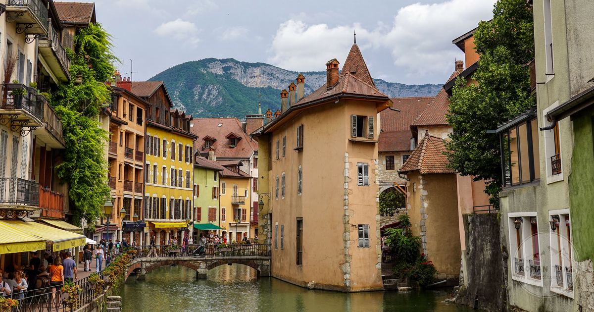 A canal and historic buildings below the mountains at Annecy, France