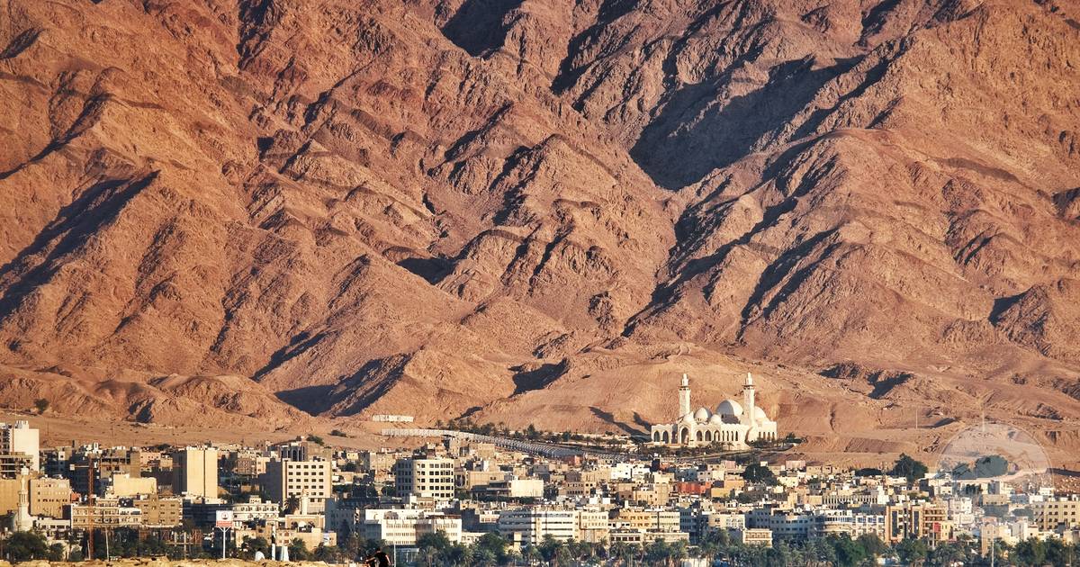 Aqaba city on the Red Sea framed by red desert mountains in Jordan, Aqaba packing list for women by Roman Trail Outfitters