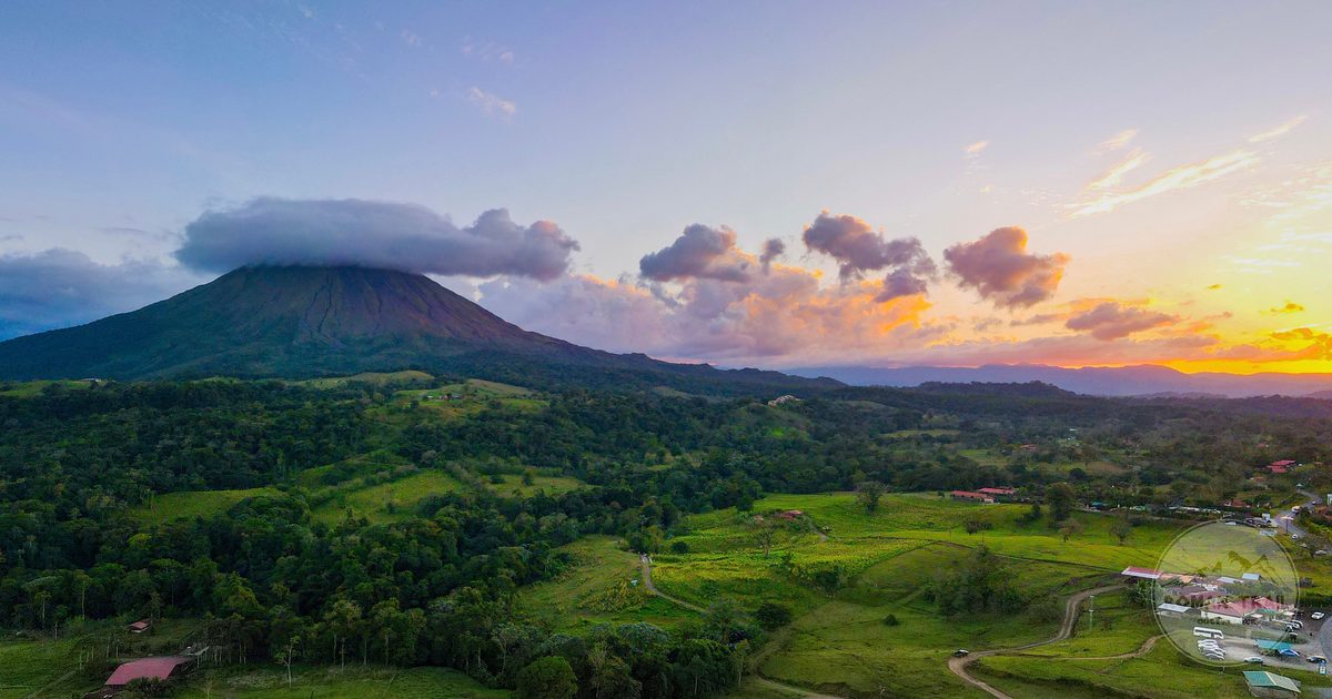 Aerial view of Arenal volcano at sunset above dense green forest, Arenal packing list for women by Roman Trail Outfitters