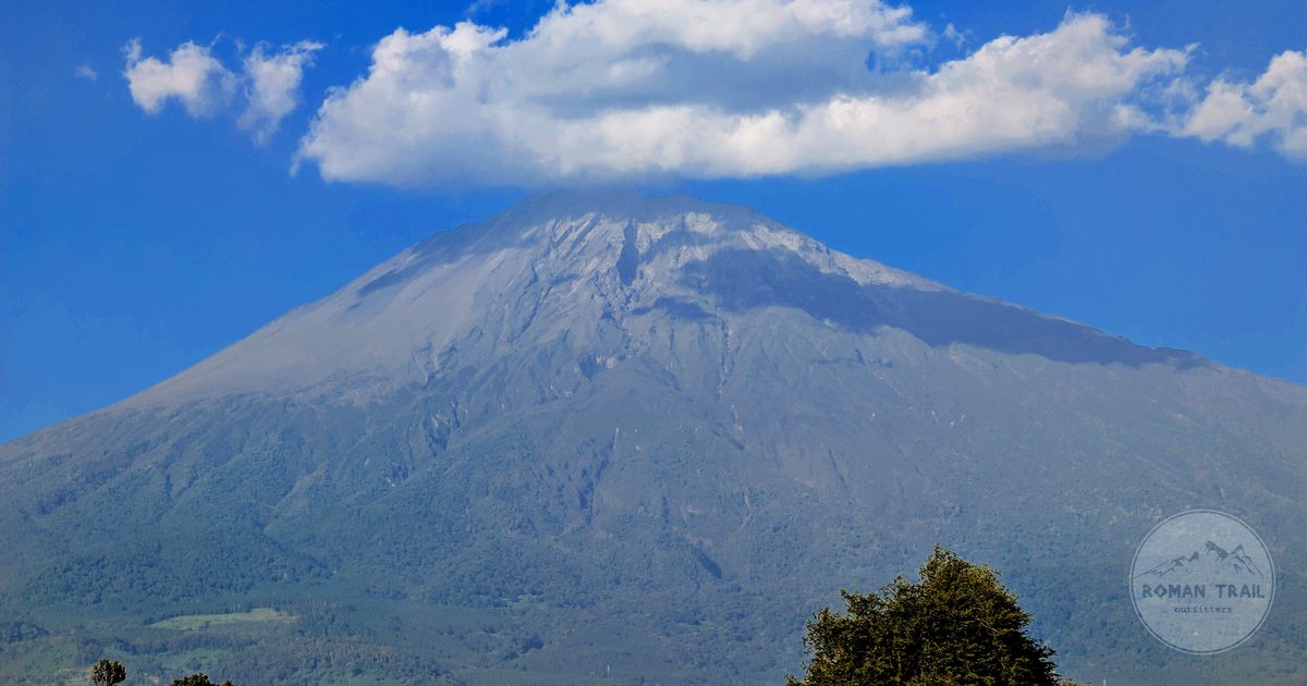 Mount Meru under cloud above green country near Arusha, Arusha packing list for women by Roman Trail Outfitters