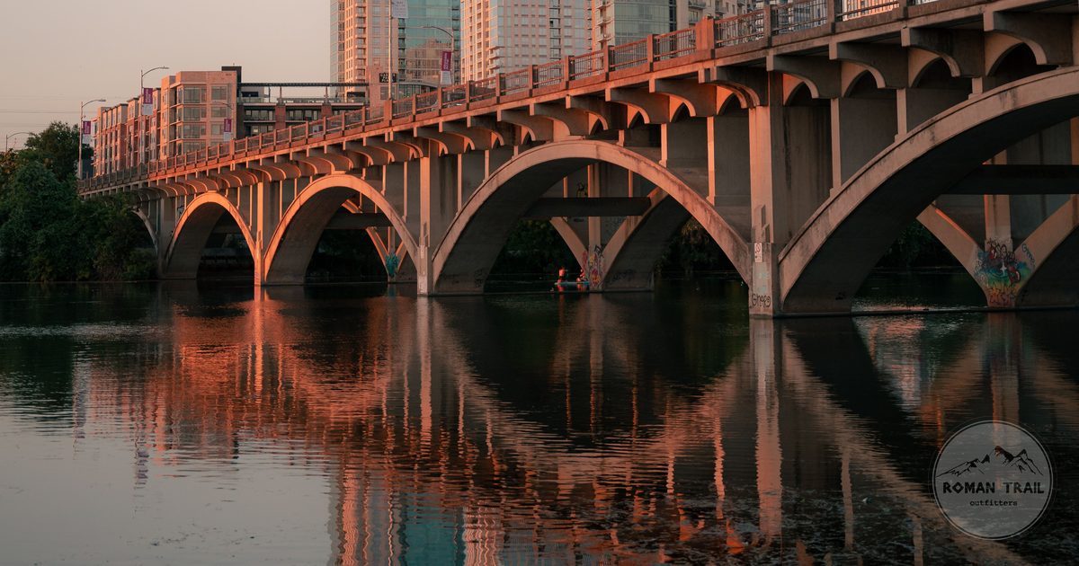 Lamar Boulevard Bridge reflected in Lady Bird Lake at sunset, Austin travel guide for women by Roman Trail Outfitters