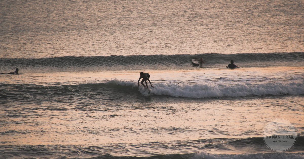 Surfer riding a wave at sunset on a south Bali beach, Indonesia