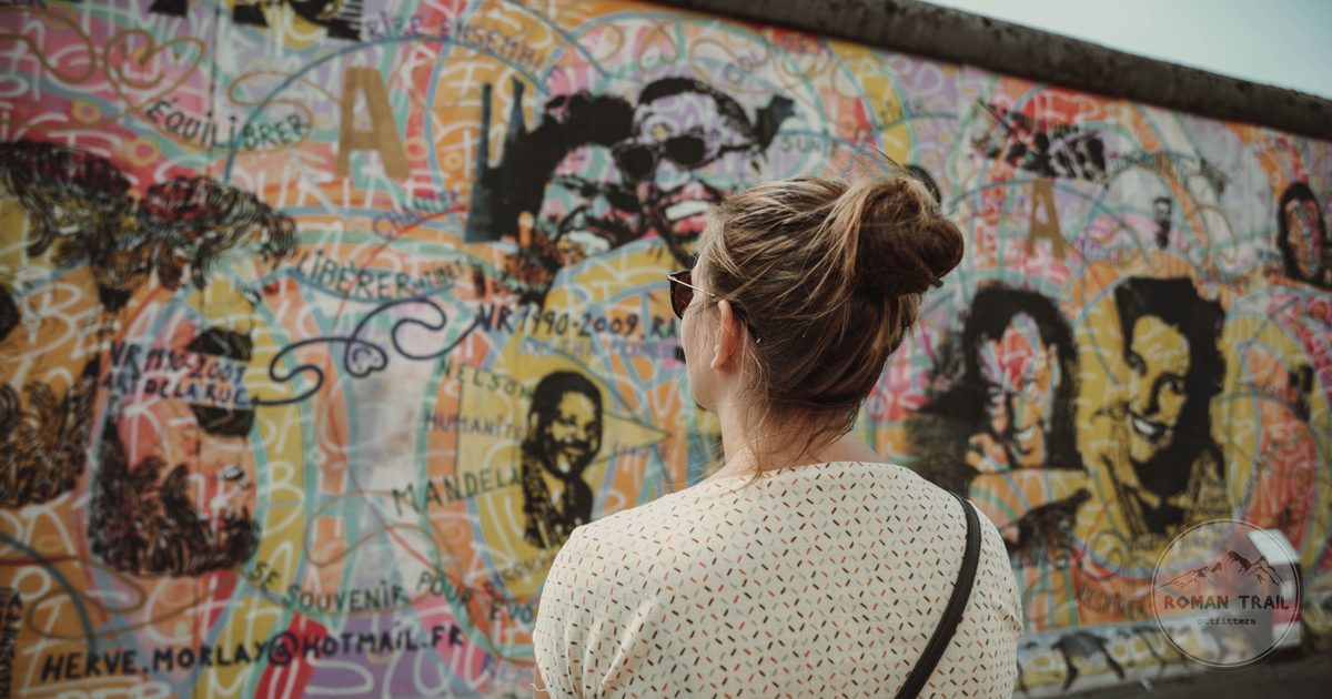A woman viewing graffiti art on the historic Berlin Wall, Germany