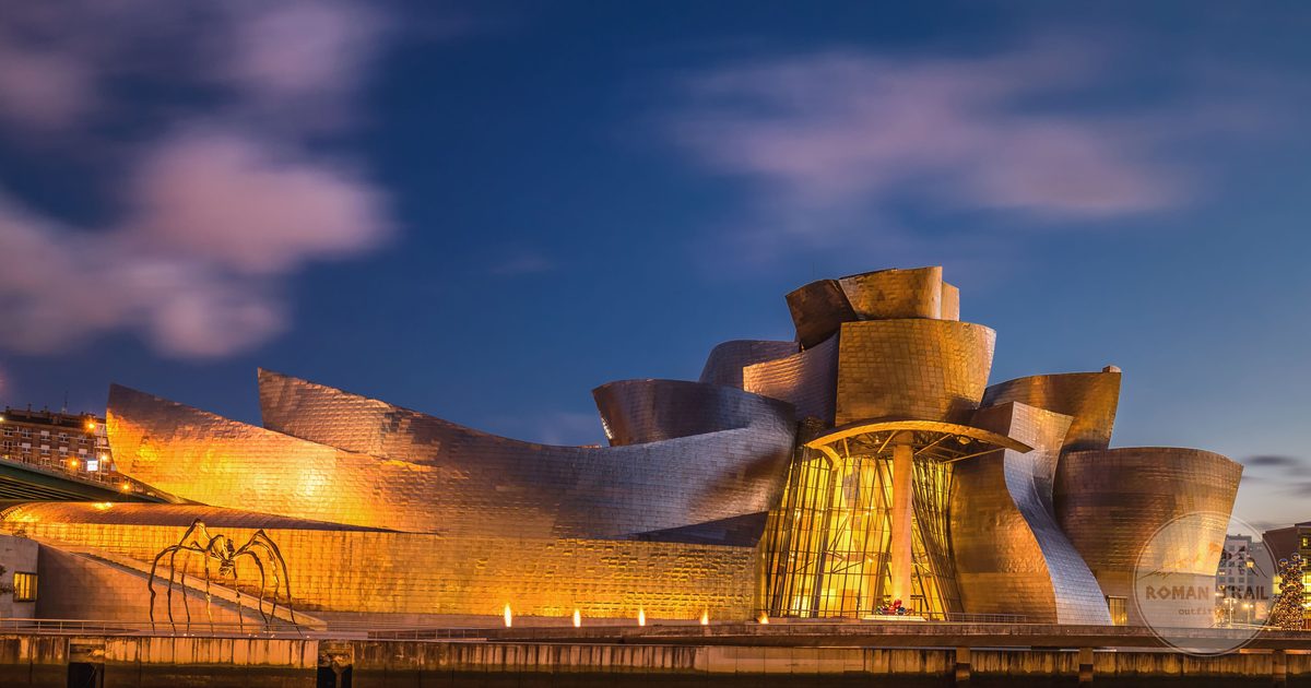 The Guggenheim Museum Bilbao lit against an evening sky, Bilbao packing list for women by Roman Trail Outfitters