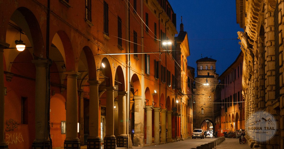 A lit Bologna portico in the evening with historic facades, Bologna packing list for women by Roman Trail Outfitters