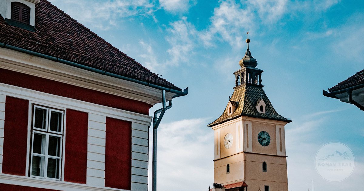 A clock tower above red rooftops in Brasov, Romania