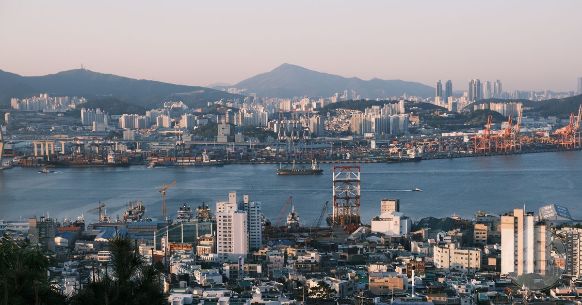The working port of Busan at sunrise with cranes and the city behind it, Busan packing list for women by Roman Trail Outfitters