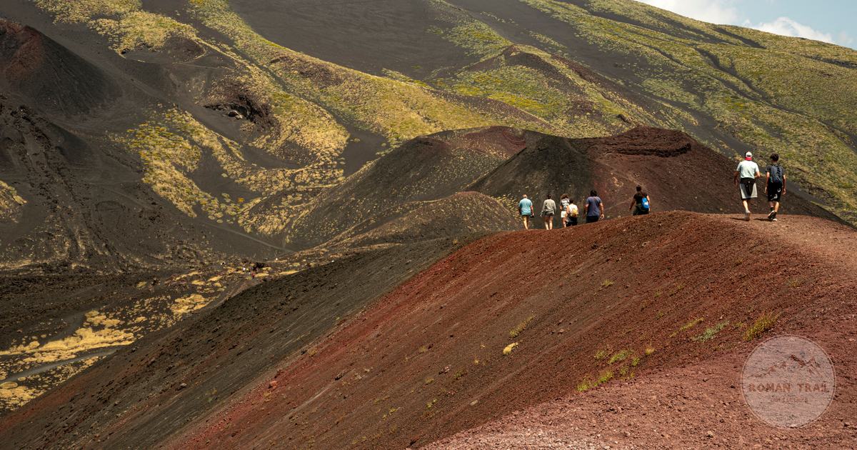 Walkers crossing the black volcanic ground of Mount Etna, Catania packing list for women by Roman Trail Outfitters
