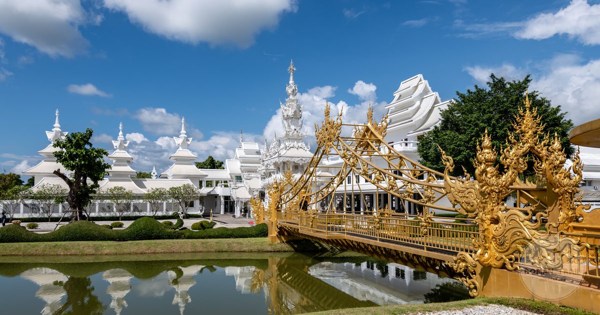 Wat Rong Khun and its bridge reflected in water, Chiang Rai, Thailand