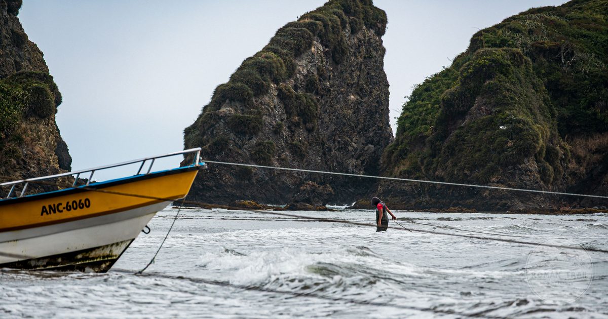 A fisherman and his boat near rocky cliffs at Ancud, Chile
