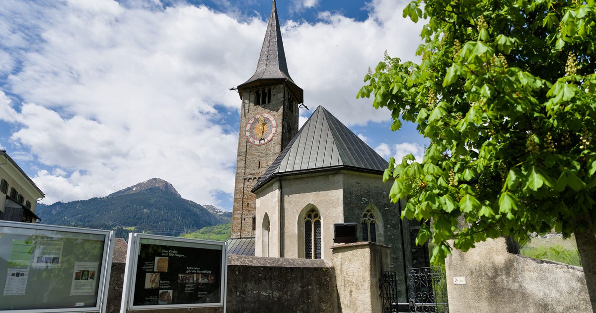 A church with a clock tower against the mountains in Grisons, Switzerland