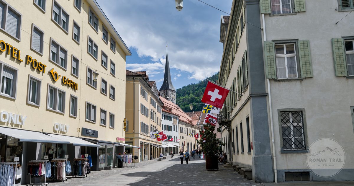 A street with a church spire and Swiss flags in Grisons, Switzerland