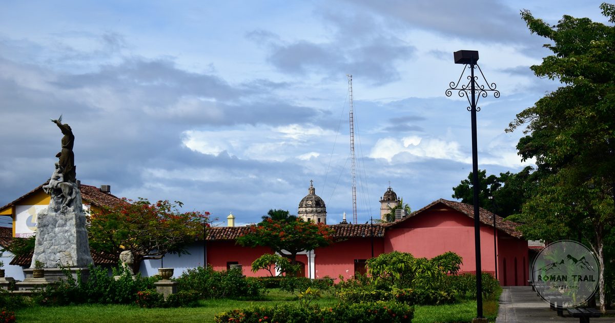 A statue and colonial architecture on a town square under cloud