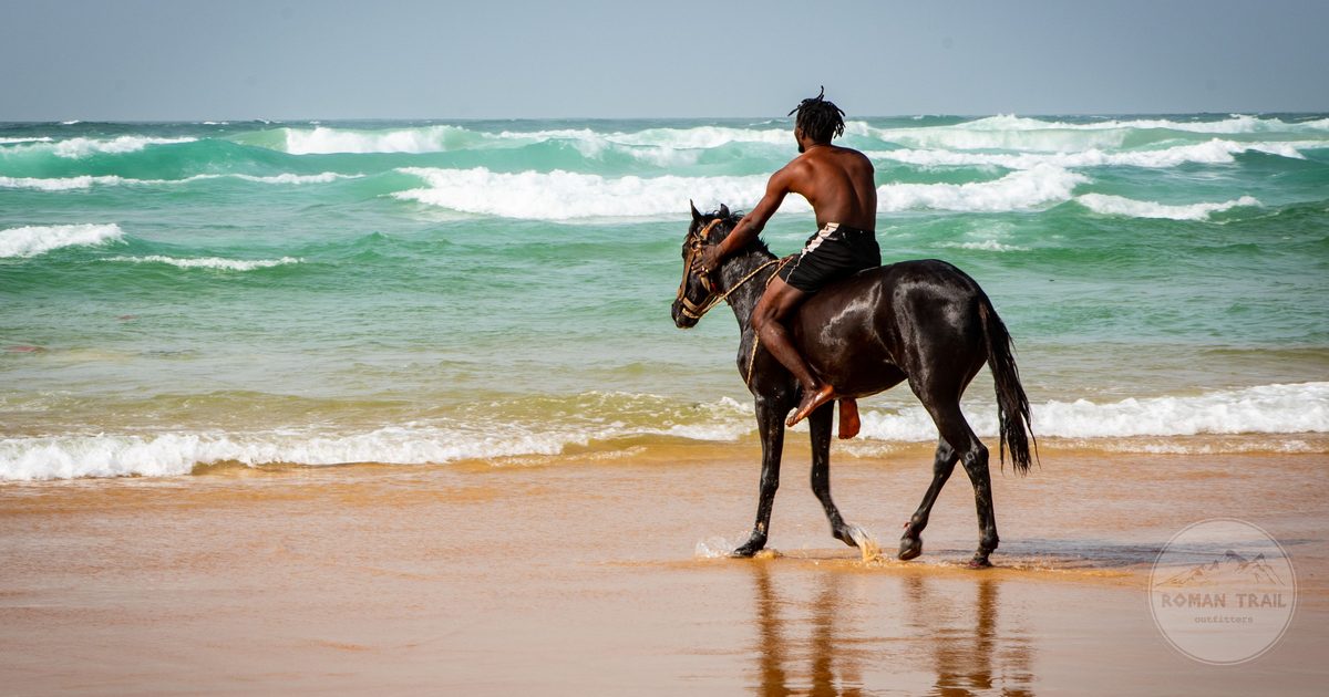 A man riding a horse along the beach in Dakar, Senegal
