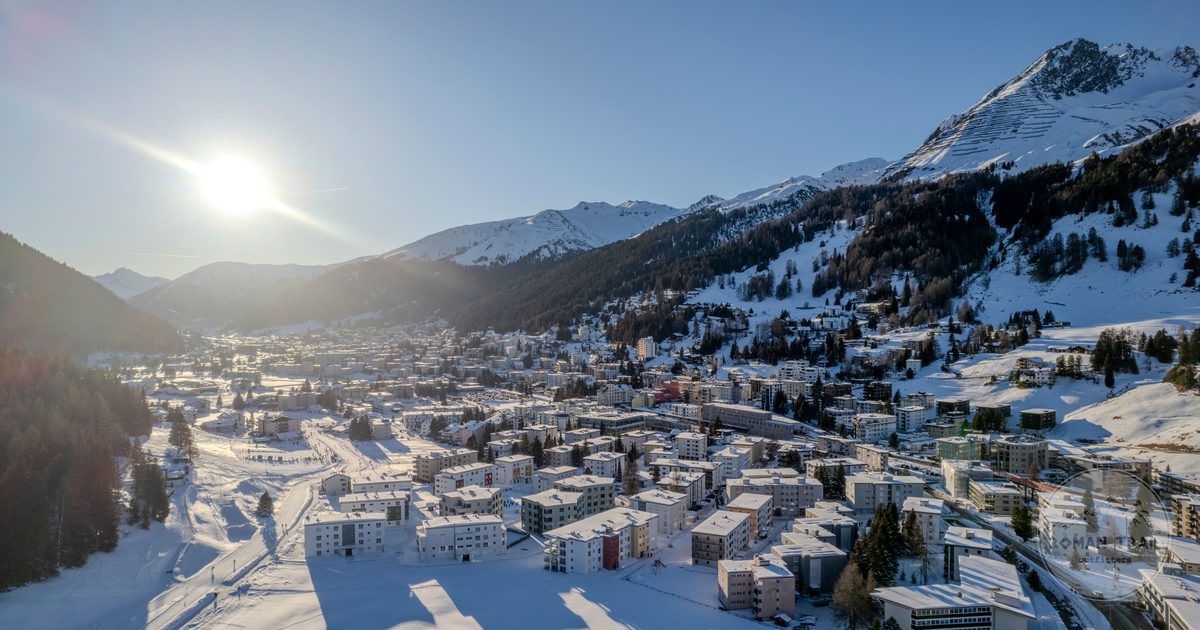 Aerial view of snow covered Davos with sunlit mountains, Switzerland