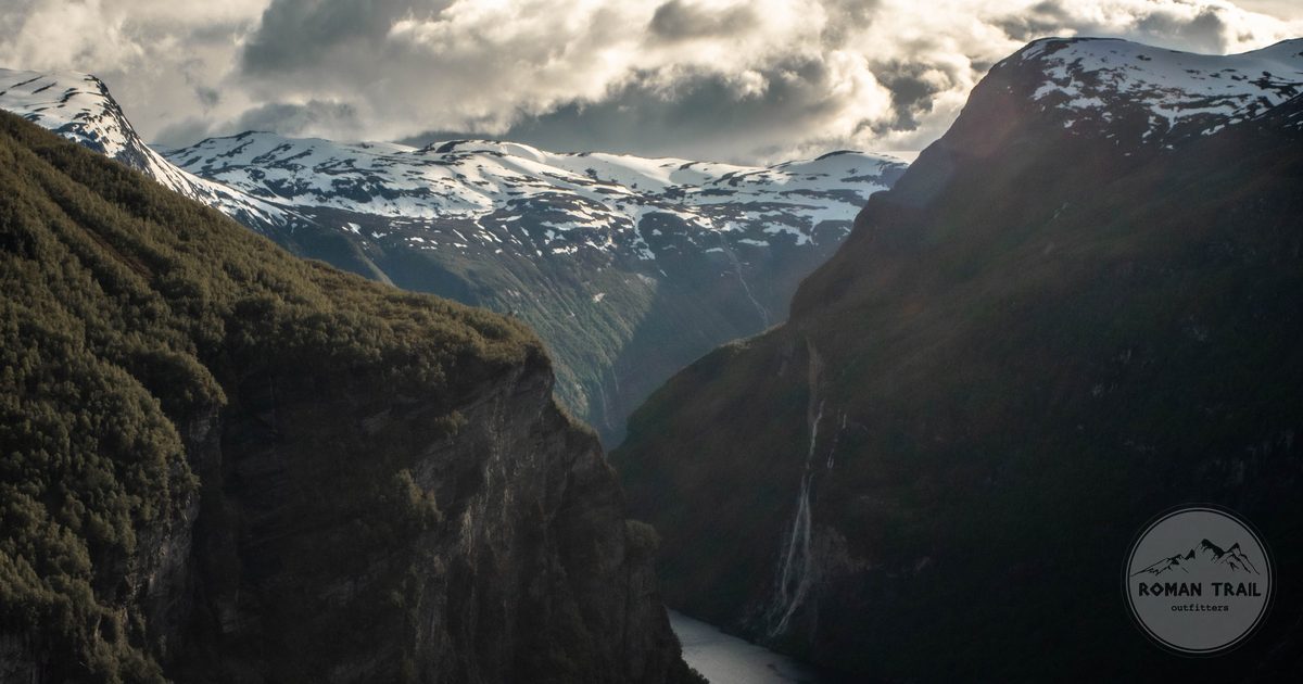 Geirangerfjord between steep cliffs with snow on the peaks above, Norway
