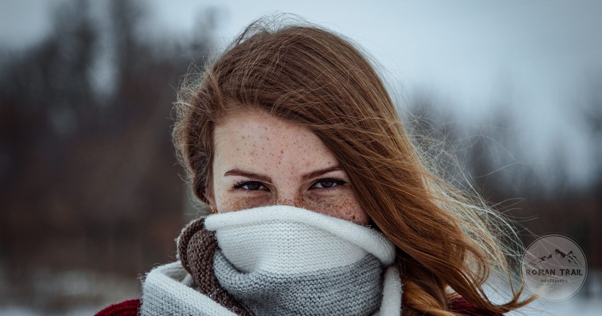 A woman wrapped in a wool scarf against a plain background