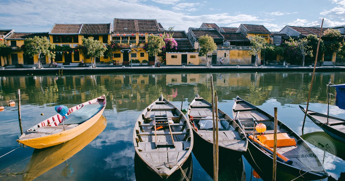Traditional wooden boats on the Thu Bon River reflecting the yellow Ancient Town facades, Hoi An travel guide for women by Roman Trail Outfitters