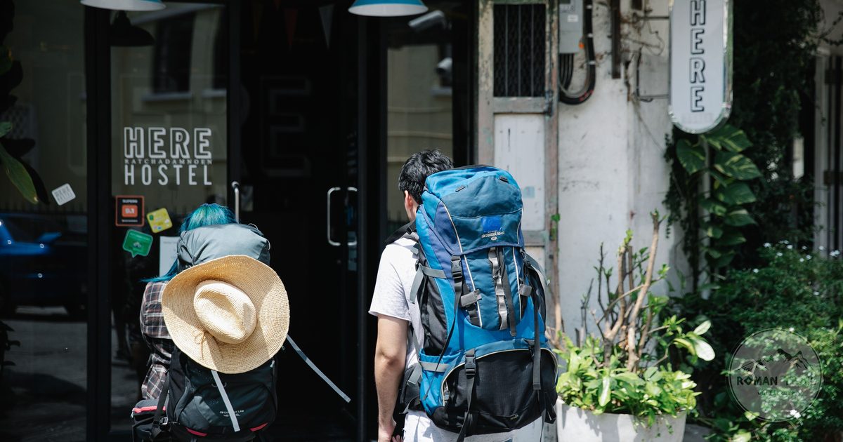Two backpackers at the entrance of a modern hostel