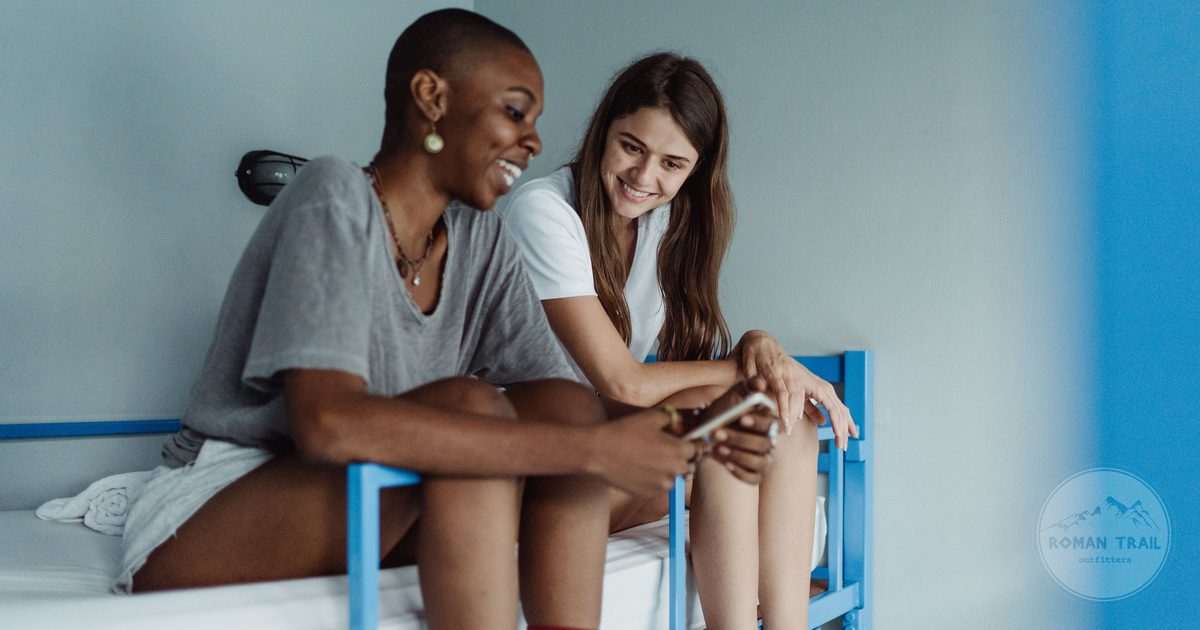 Two women chatting on bunk beds in a modern hostel room