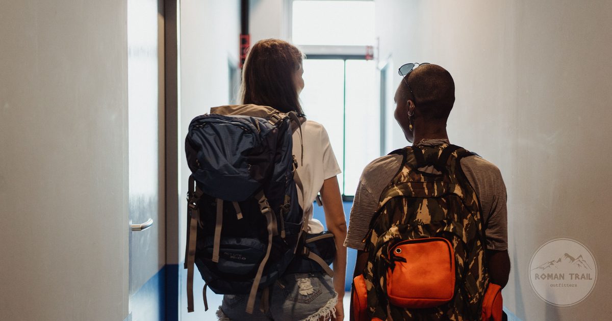 Two friends walking a hostel corridor with backpacks