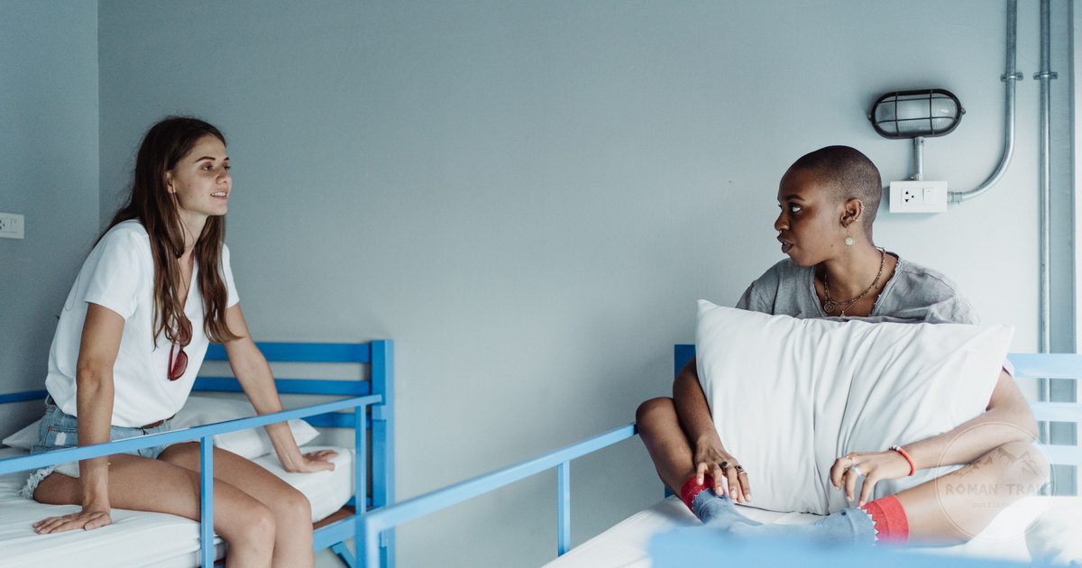 Two women in conversation on bunk beds in a hostel