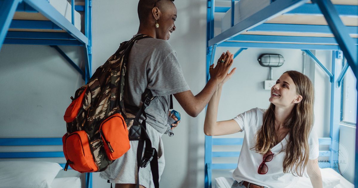 Two women travellers in a bright hostel dorm room
