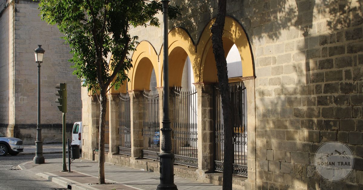 An arched facade and trees on a street in Jerez de la Frontera, Spain