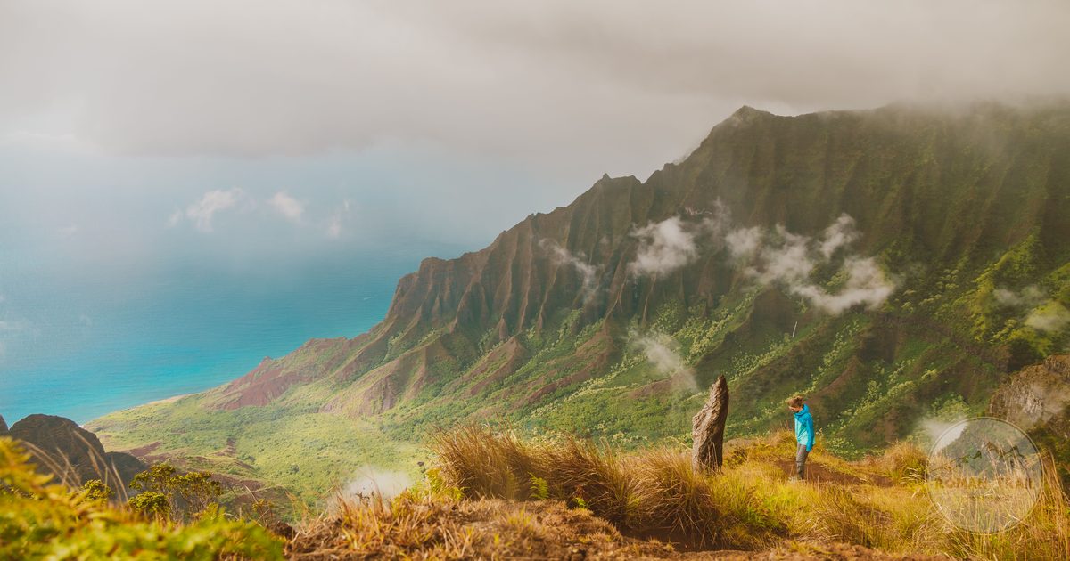 A hiker looking out over the misty Na Pali coast on Kauai, Hawaii