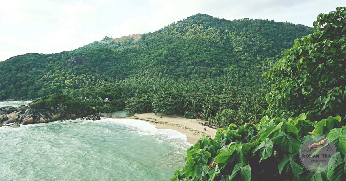 A beach below green hills on Koh Phangan, Thailand