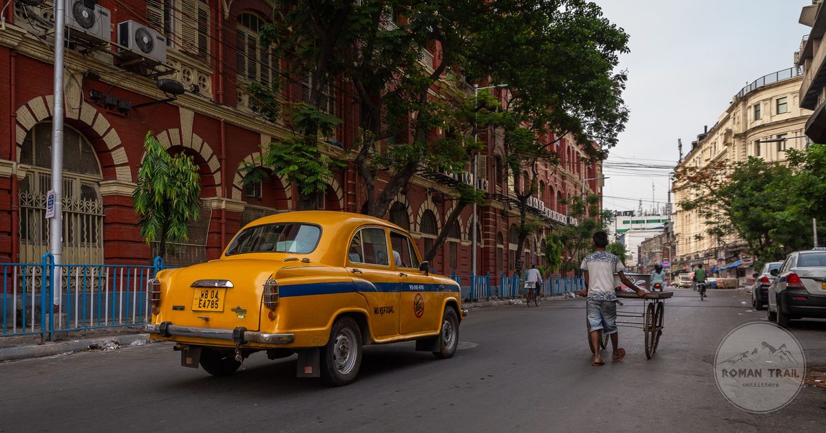 A yellow Ambassador taxi on a busy Kolkata street, Kolkata packing list for women by Roman Trail Outfitters