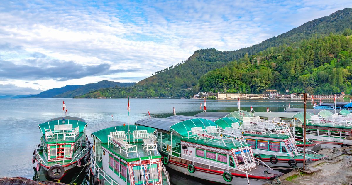 Colourful boats docked on Lake Toba among green hills, Indonesia