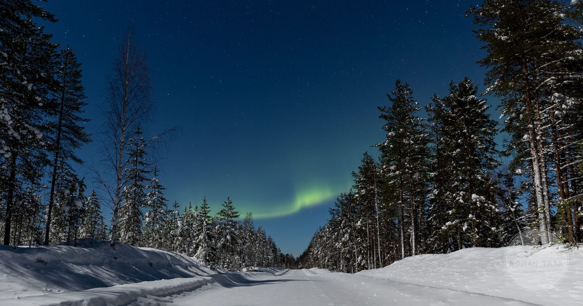 Aurora borealis above a snowy road in Finnish Lapland