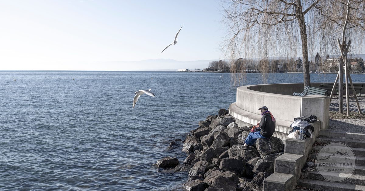 The shore of Lake Geneva at Lausanne with mountains across the water, Lausanne packing list for women by Roman Trail Outfitters