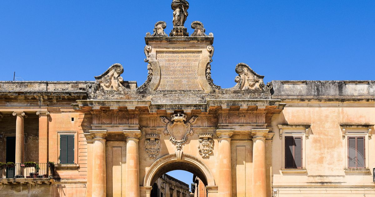 An ornate historical archway under clear sky in Lecce, Apulia, Italy