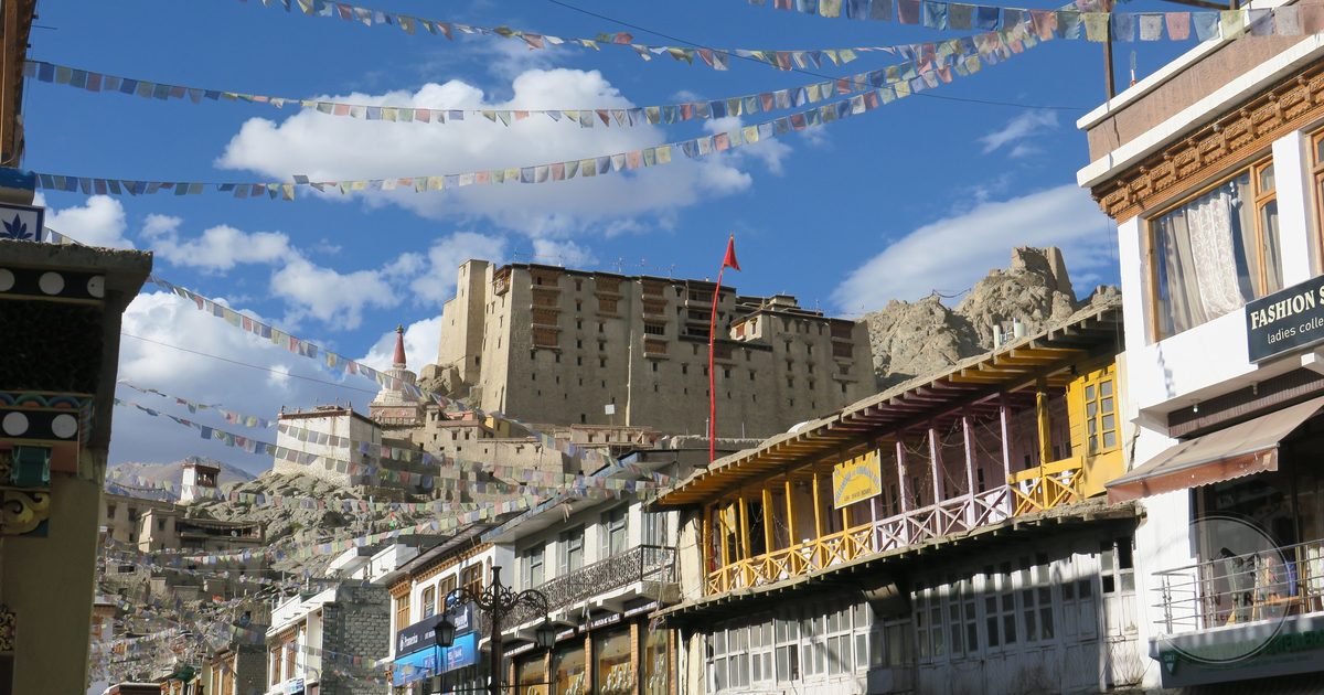 A street in Leh with prayer flags and the palace above, Ladakh, India