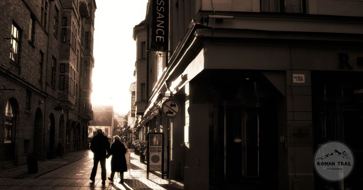 Two people silhouetted on a historic street in Malmö, Sweden, at sunset