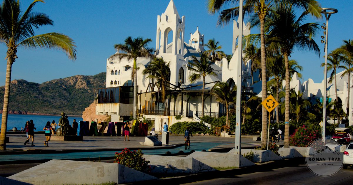 People on the Mazatlan seafront among palms and low buildings, Mexico