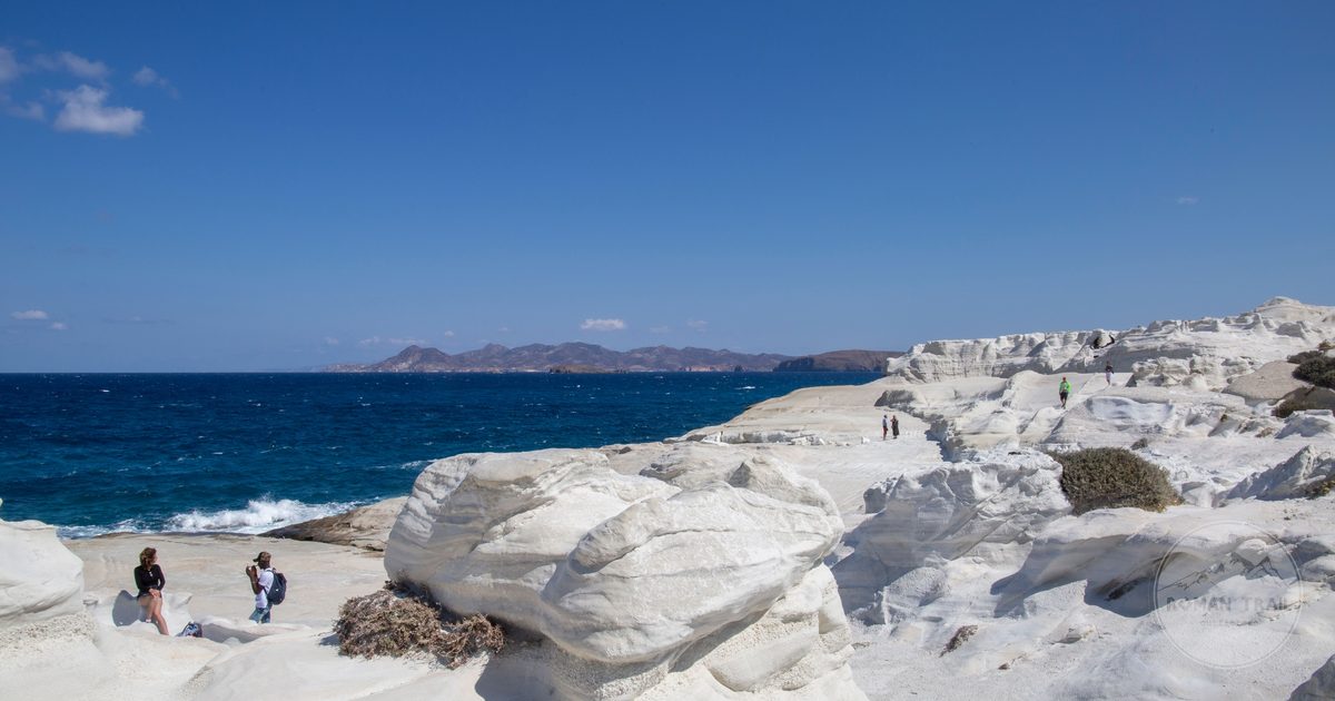 The white rock coastline of Milos above turquoise sea, Milos packing list for women by Roman Trail Outfitters