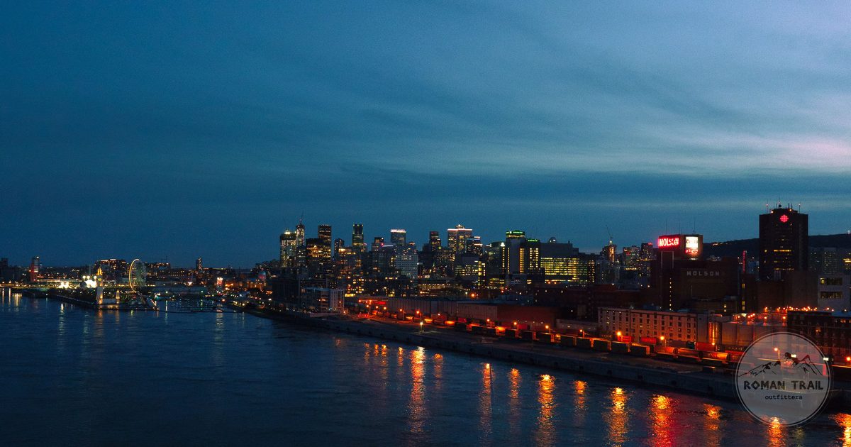 Montreal skyline at dusk with city lights reflected in the river, Montreal travel guide for women by Roman Trail Outfitters