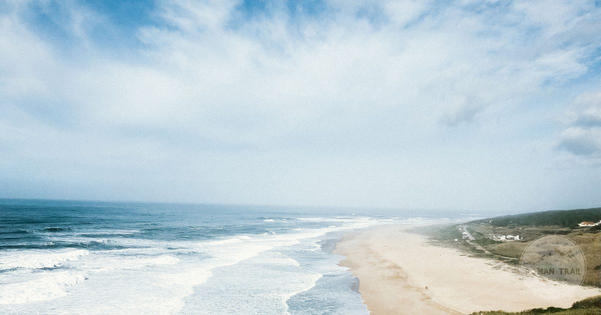Aerial view of the wide sandy beach and town of Nazare, Nazare packing list for women by Roman Trail Outfitters