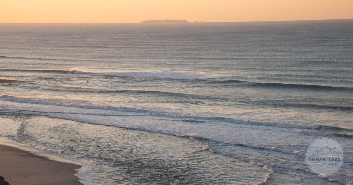 Sunrise over the ocean and beach at Nazare in Portugal, Nazare packing list for women by Roman Trail Outfitters