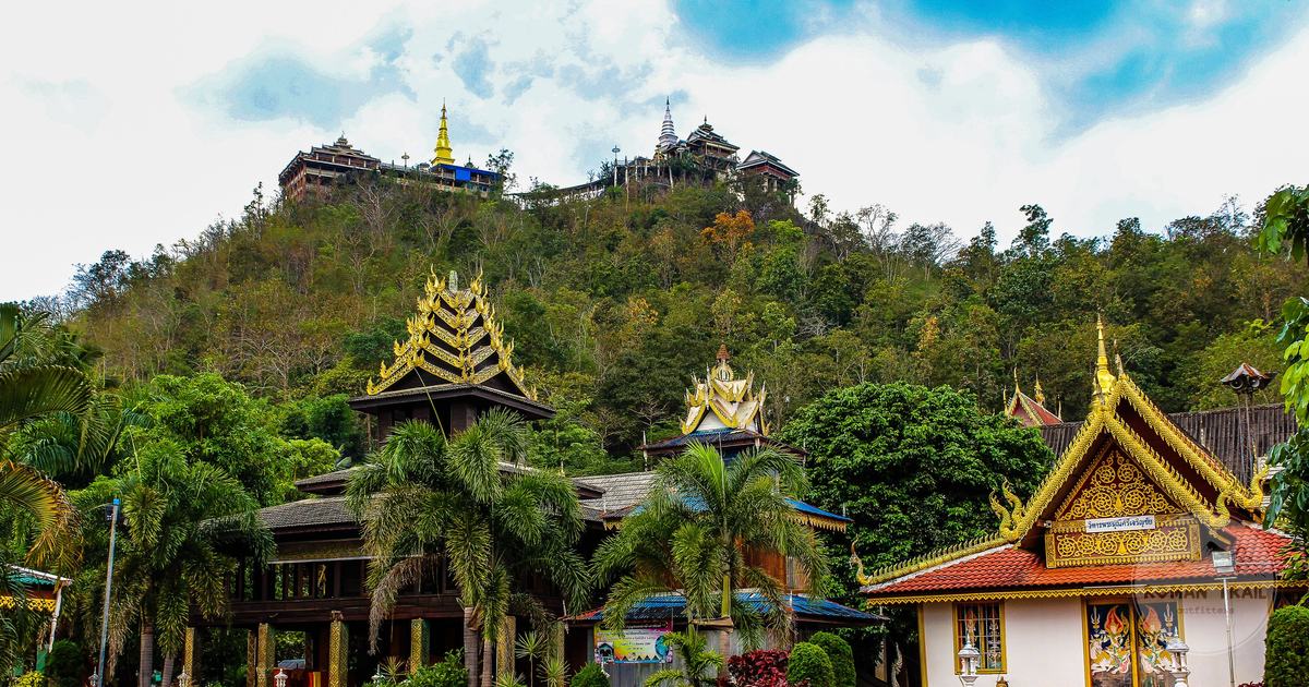 Golden-roofed temples among forested hills in northern Thailand