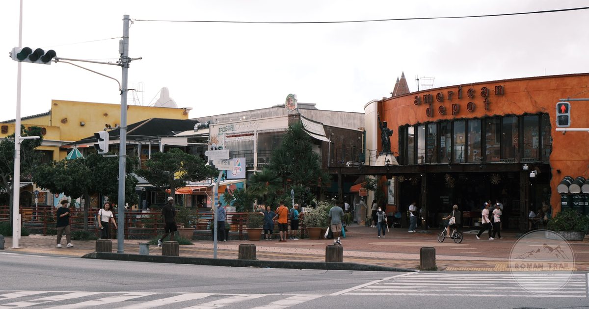 A colourful shopping street in Okinawa with palm trees and low buildings, Okinawa packing list for women by Roman Trail Outfitters