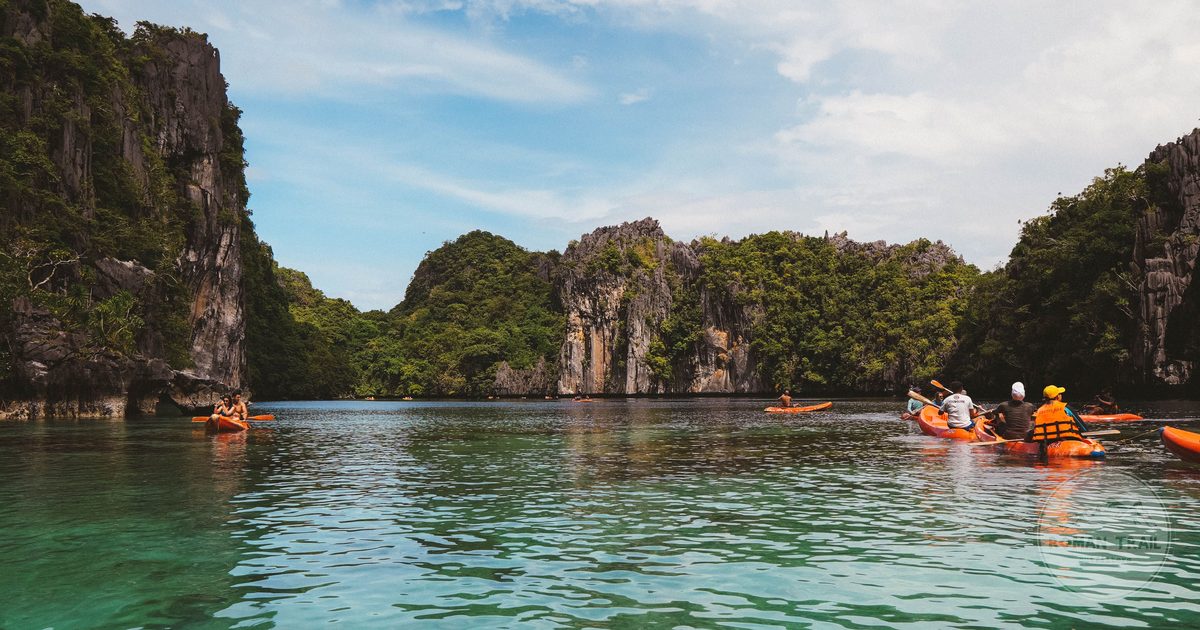 Kayakers paddling beneath limestone cliffs in El Nido, Palawan